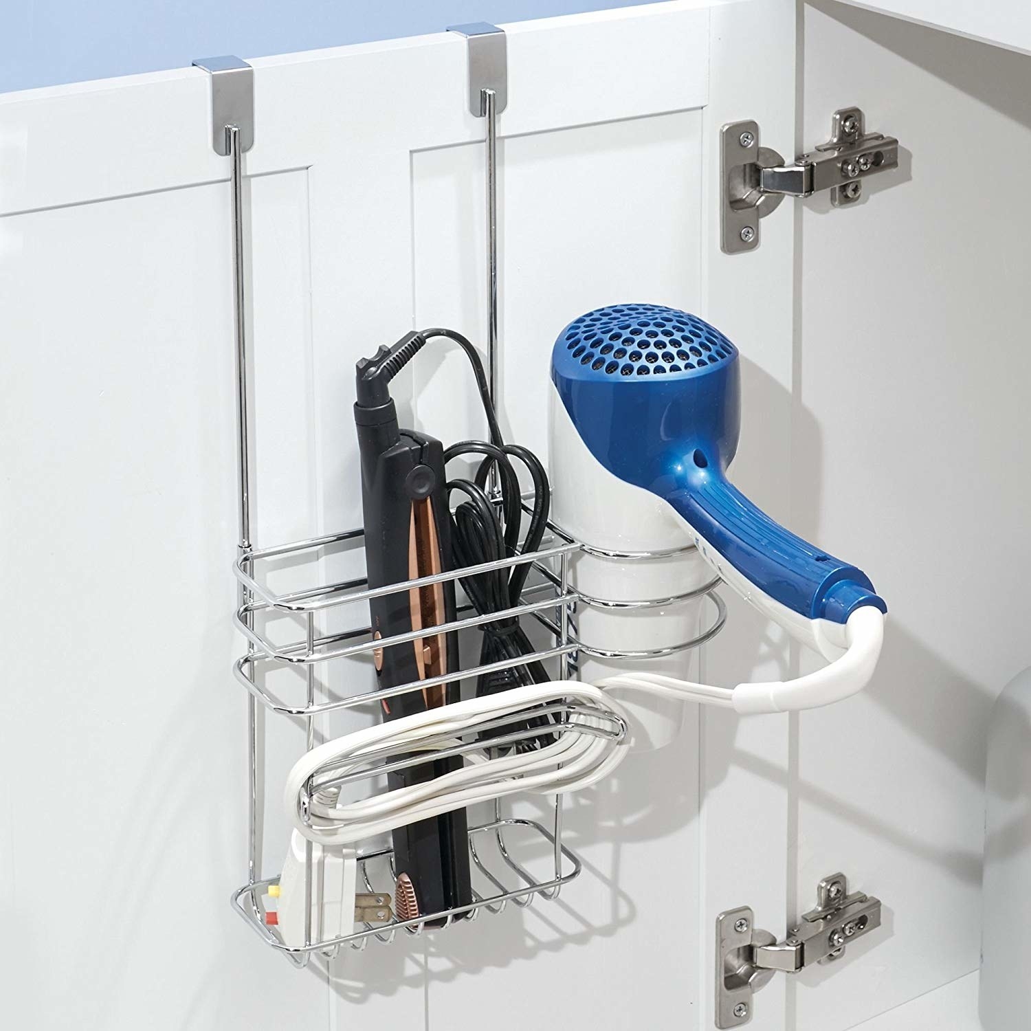 a silver tool organizer hanging over a cabinet door with a spot to hold a straightener and a spot to hold a blow dryer