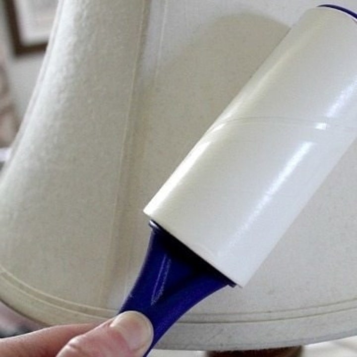 Bloggers hand using a lint roller on a lampshade