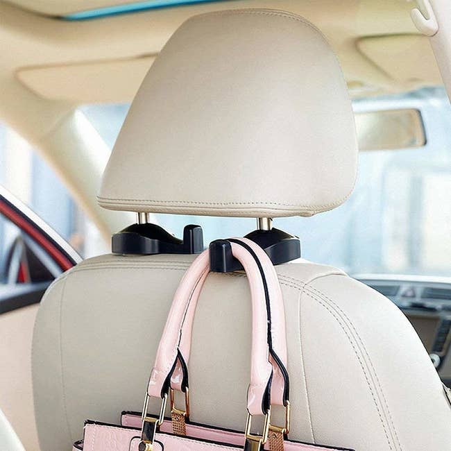 sturdy hooks attached to car headrest with a purse hanging from them 