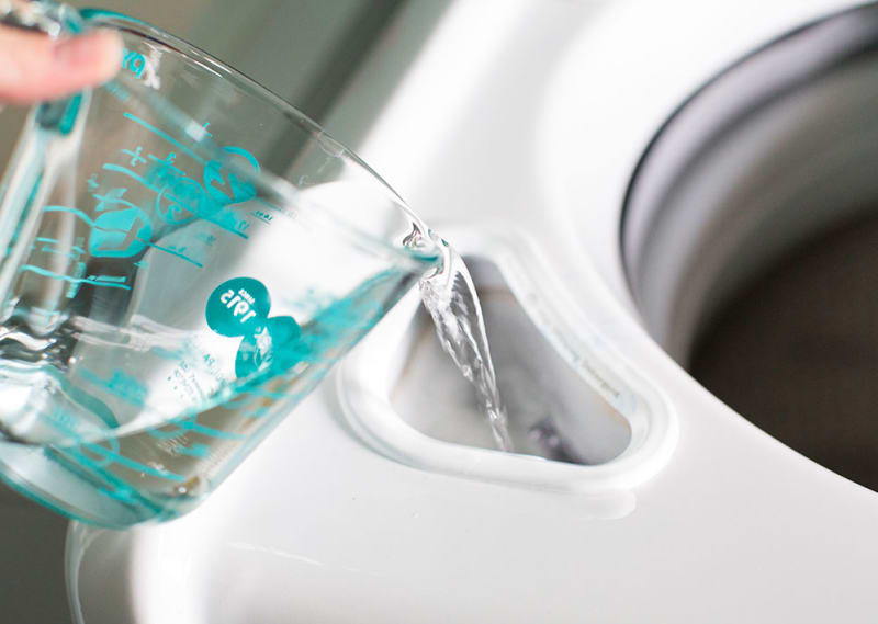 Blogger pouring vinegar into their washer&#x27;s detergent compartment