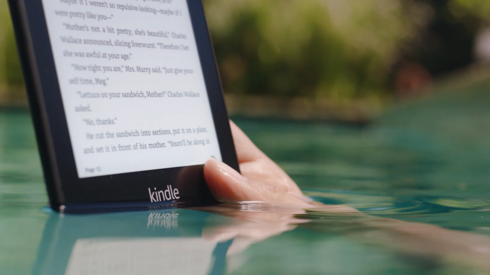 a hand holding the Kindle in a body of water
