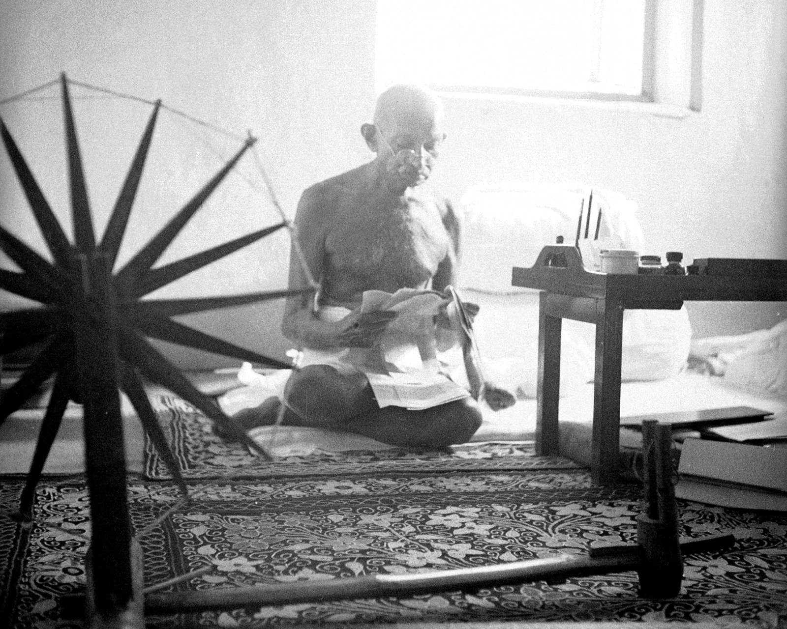 O líder indiano Mahatma Gandhi lê sentado no chão em sua casa, em 1946.