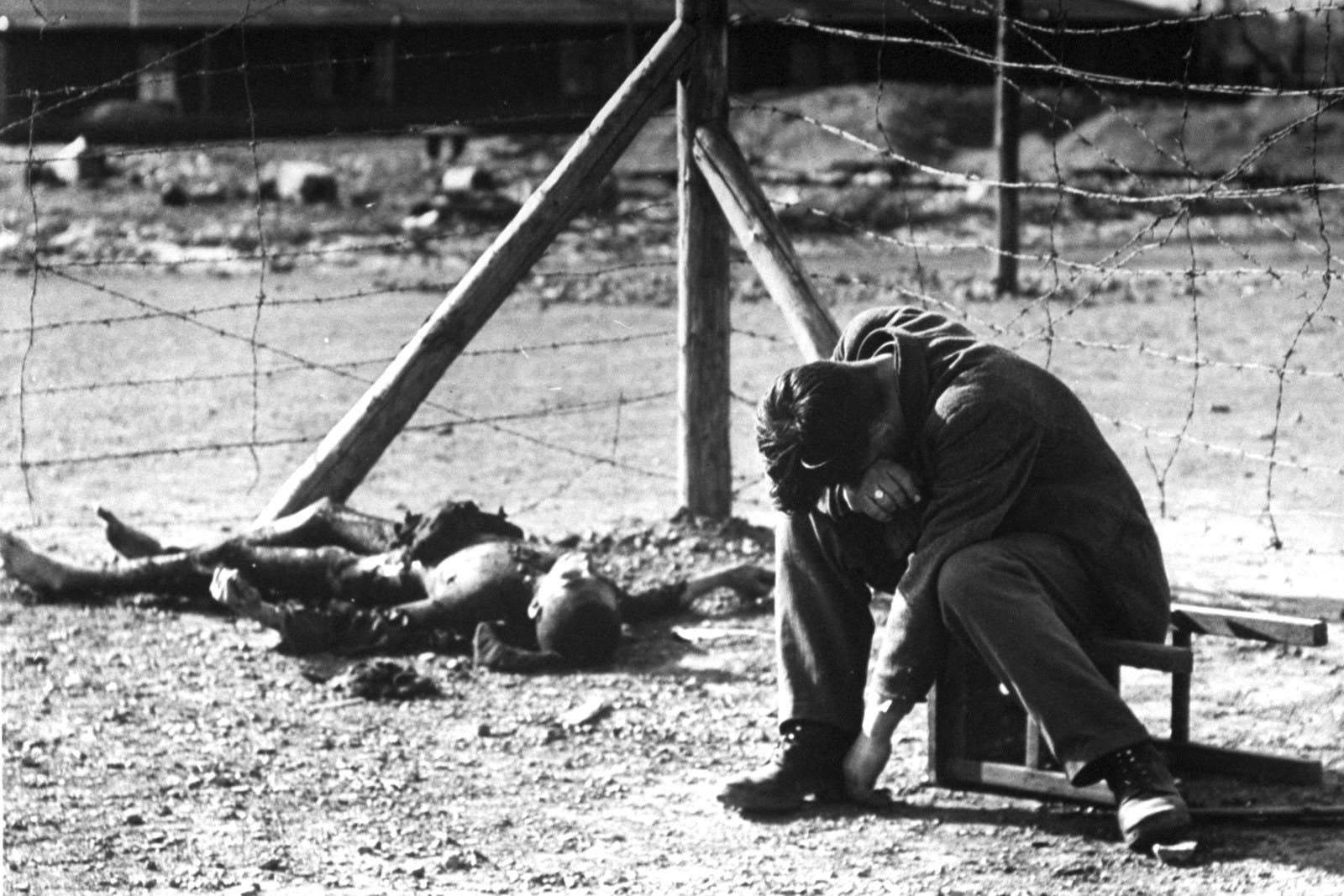 Homem chora perto de um cadáver carbonizado no campo de trabalhos forçados Erla, em maio de 1945.