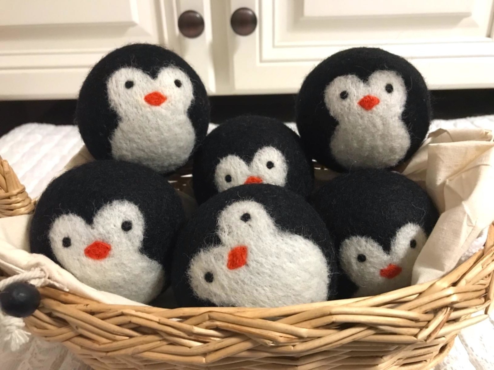 black and white wool dryer balls that look like little penguin faces
