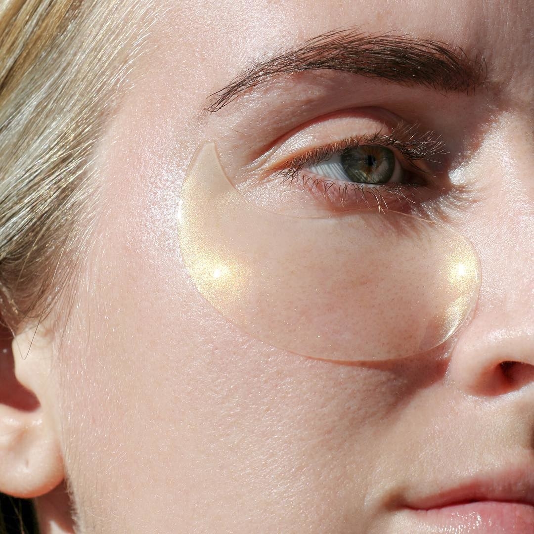 Close up of a model wearing the patch, which is teardrop shaped and translucent gold 