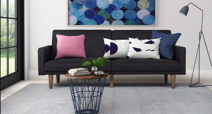 A display of the sofa with a coffee table in front and multicolored throw pillow sitting on the sofa