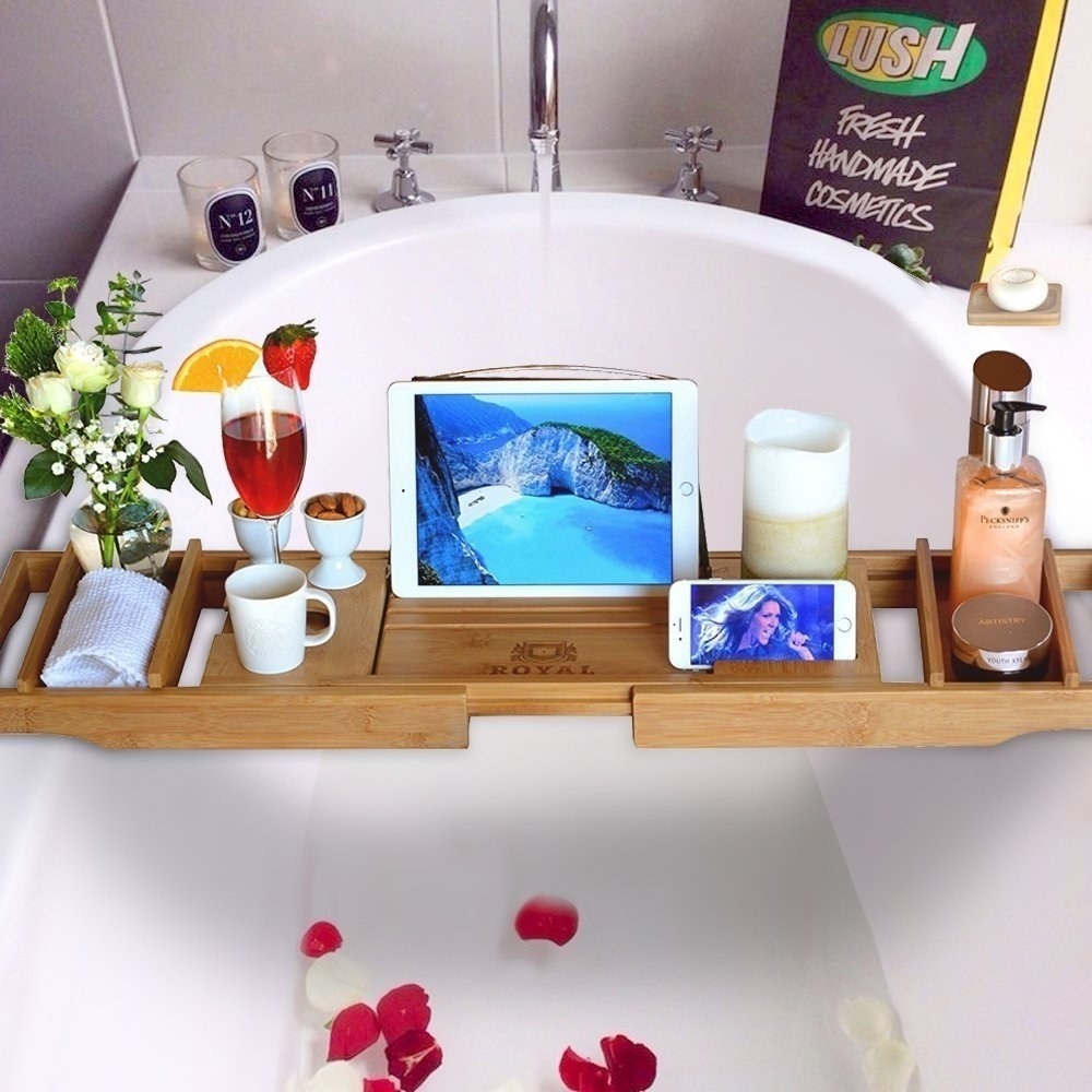 The bathtub tray with an iPad, drinks, flowers, candle, and more on it.