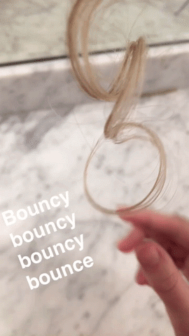 GIF of Maitland pulling her curls down with the text: Bouncy, bouncy, bouncy, bounce