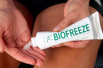 A person squeezing a tube of Biofreeze onto their fingers