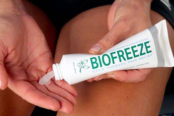A person squeezing a tube of Biofreeze onto their fingers