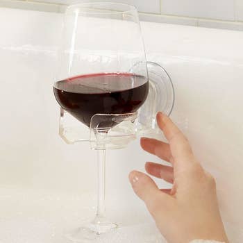 wine glass in bubble bath held on the side of the tub with a suction cup holder