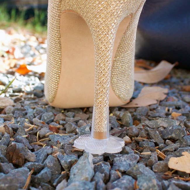 A heel stopper on a pair of high heels placed on gravel