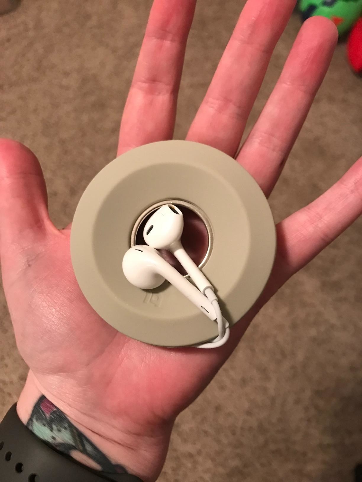 round piece of silicone with headphones wrapped around it in reviewer&#x27;s hand