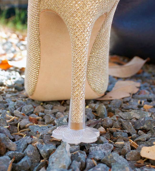 plastic flower-shaped cap on stiletto heel keeping it from sinking into gravel