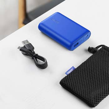 The blue, slightly-larger-than-palm-size power bank with the cord and case