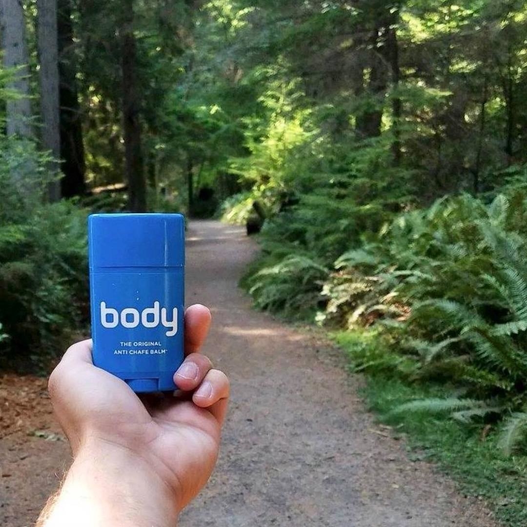 A hand holding the deodorant stick-shaped product before a hike