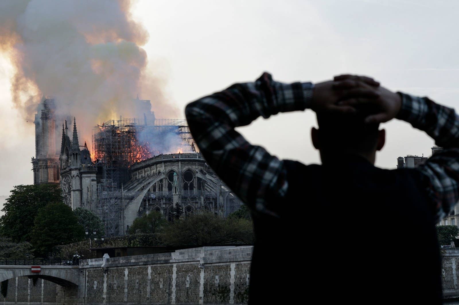 A man watches the landmark Notre-Dame Cathedral, engulfed in flames, in central Paris on April 15, 2019.