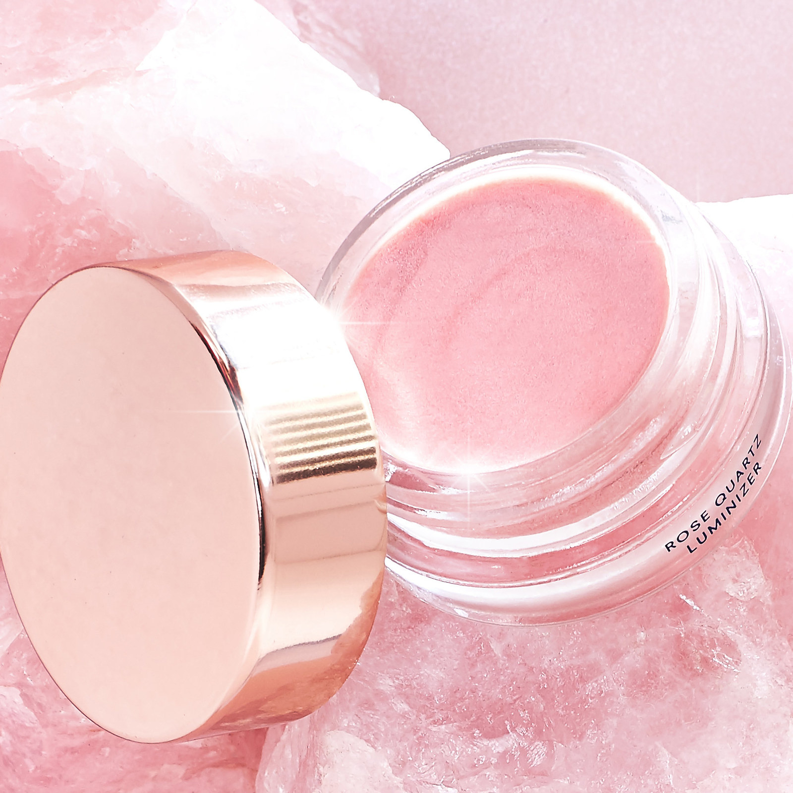 a glass makeup pot with pink glittery product inside