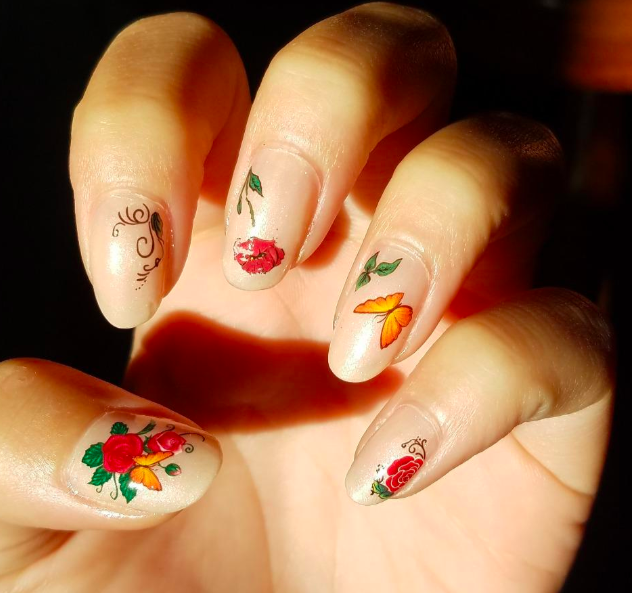 decal stickers with roses and butterflies on model&#x27;s nails
