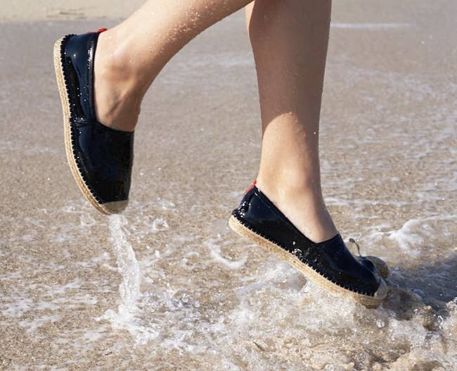 Model wearing the espadrilles while jumping in the water at the beach