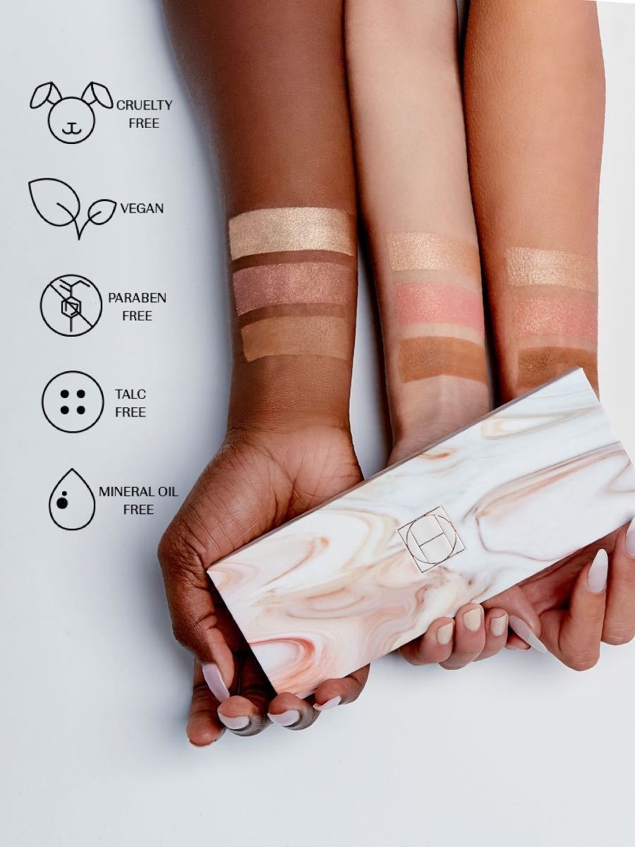 the arms of three models showing the way the colors of the eyeshadows look on different skintones while holding the palette