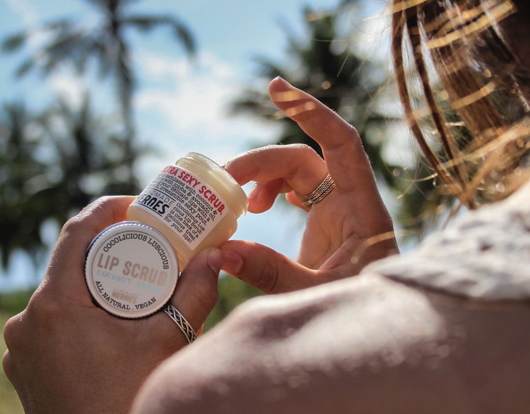 A hand scooping the scrub out of the small jar