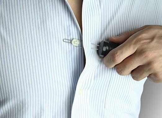 Person using the tool with on hand to pull a button through a shirt loop