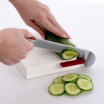person using slicer to cut cucumbers 