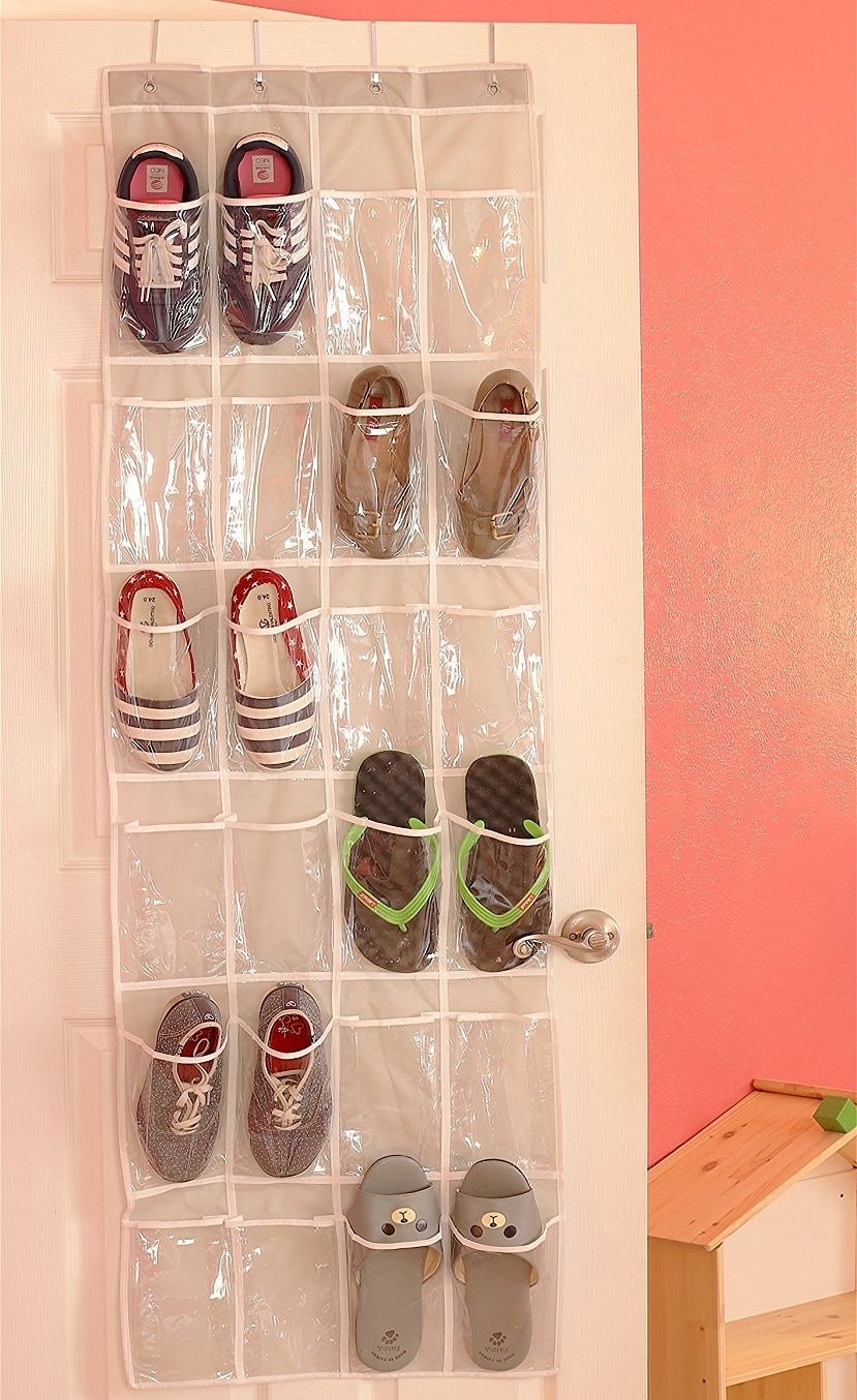 A clear over-the-door organizer with some of the pockets holding one shoe each