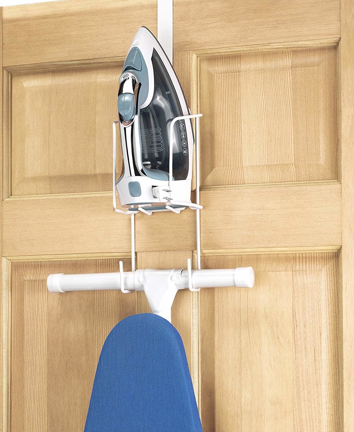 A white caddy hanging over a door holding an ironing board and an iron
