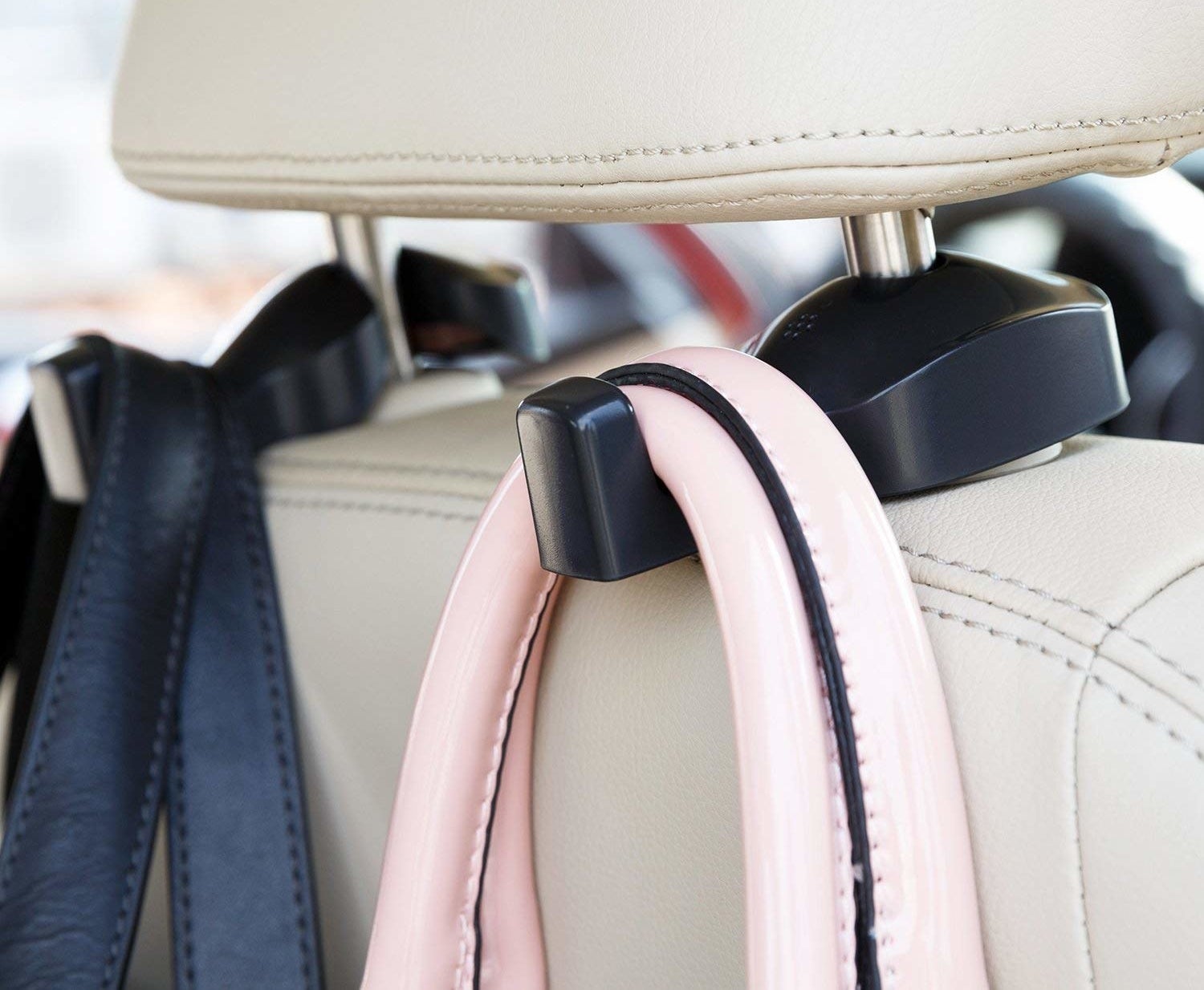 Hooks attached to the car headrest each holding what appear to be handbag straps