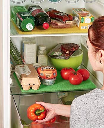 person putting veggies onto shelf with anti-mold pad