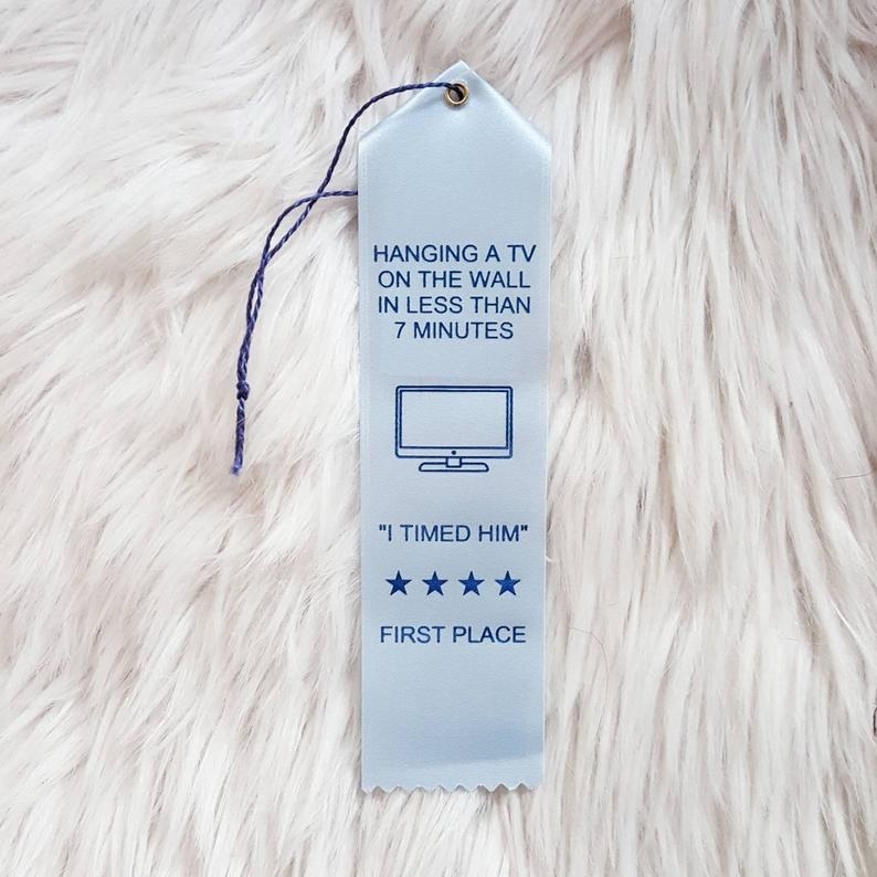 a blue award ribbon that says "hanging a tv on the wall in less than 7 minutes" on it
