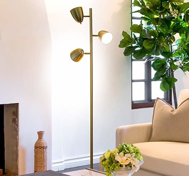 living room corner with gold tone floor lamp with three arms on it