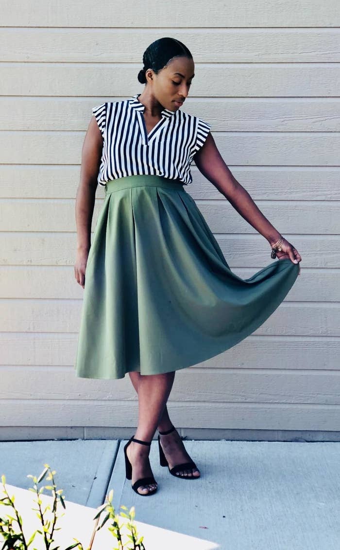 a reviewer wearing the skirt in green with heels and a striped shirt 