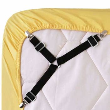 the fasteners, which look like a three-pronged overall strap, holding a fitted sheet around the underside of a mattress