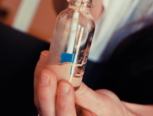 person using the spatty to get makeup out of a jar