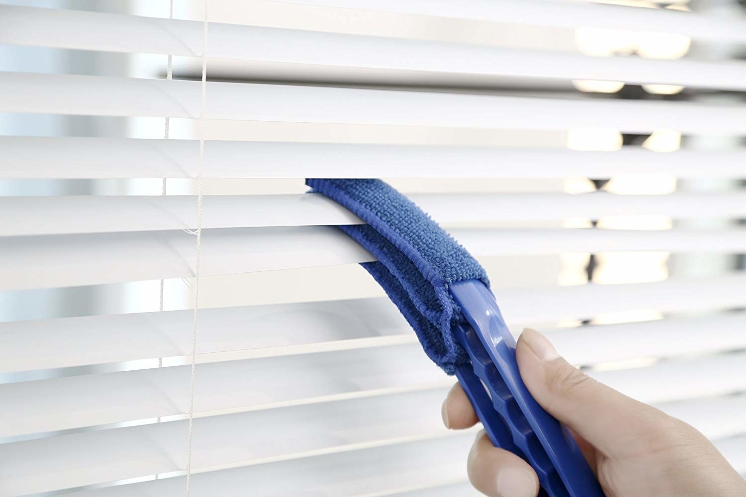 Model using microfiber duster to clean in between blinds