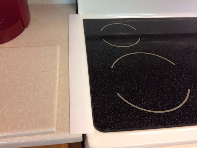 Amazon reviewer photo of white stove gap cover placed between counter and stove