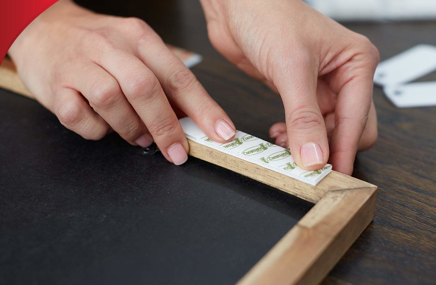 someone applying a command strip to a painting