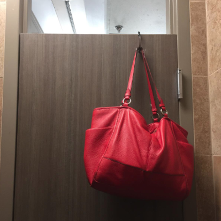 A reviewer photo of purse hanging from a restroom door  