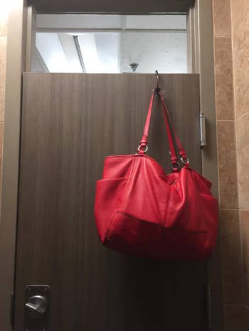 reviewer photo of purse hanging from a restroom door  