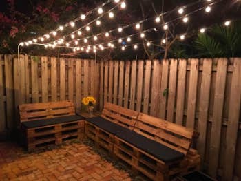 reviewer pic of lights strung up in lines above a patio area with benches