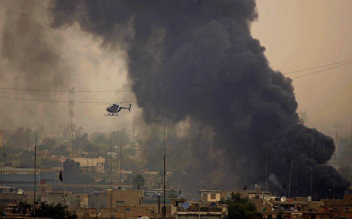 A Blackwater helicopter flies close to black smoke billowing from a fire in an area in central Baghdad on March 3, 2005.