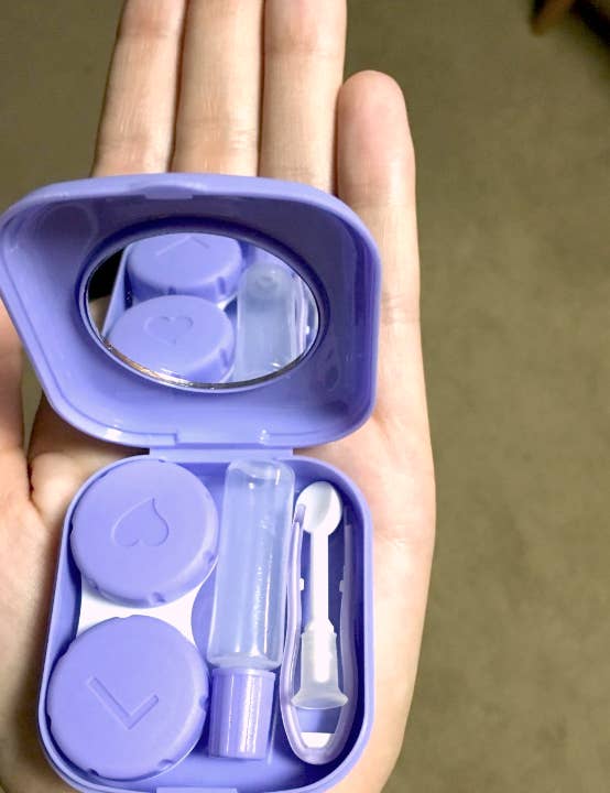 reviewer holding up a lilac case with a contact case squeeze bottle and tweezers in it