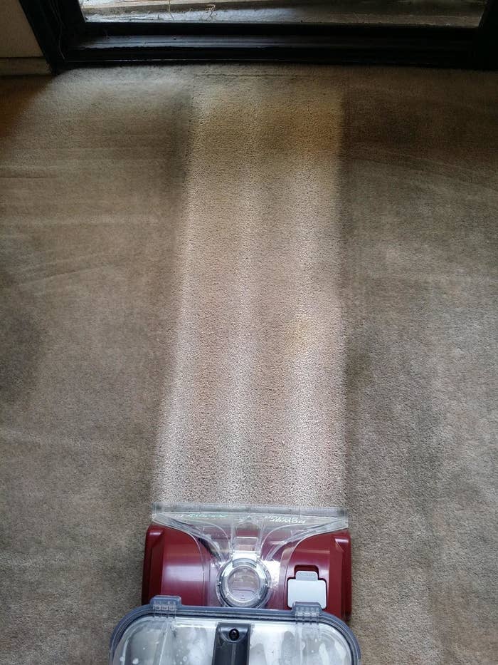 vacuum cleans a light stripe into dark and dirty carpet 