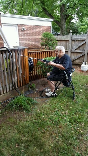 reviewer sits and sprays fence with power washer 