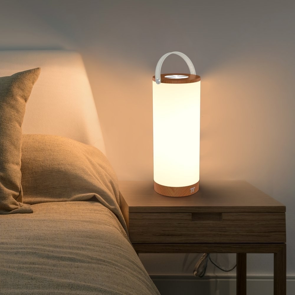 The cylindrical lamp illuminating a bedside table