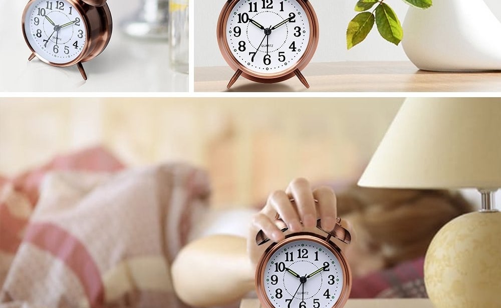 copper color alarm clock on night stand with person in bed reaching over to turn it off