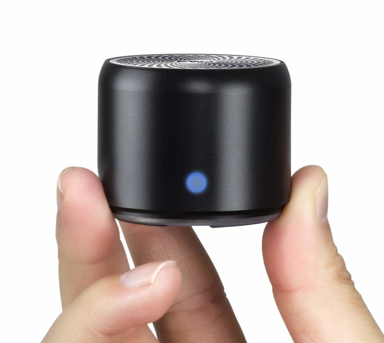 A person holding the small cylindrical speaker between their fingers